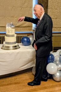 Frank Maxwell cuts the cake for a double 90th celebration